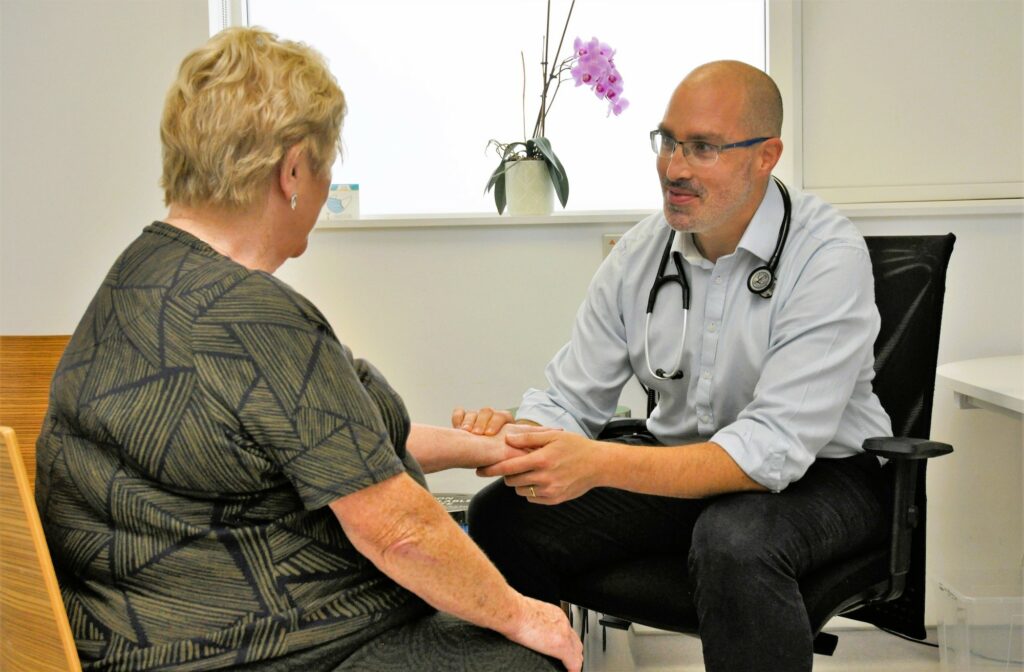 A doctor in a doctor's office taking the pulse of a woman.