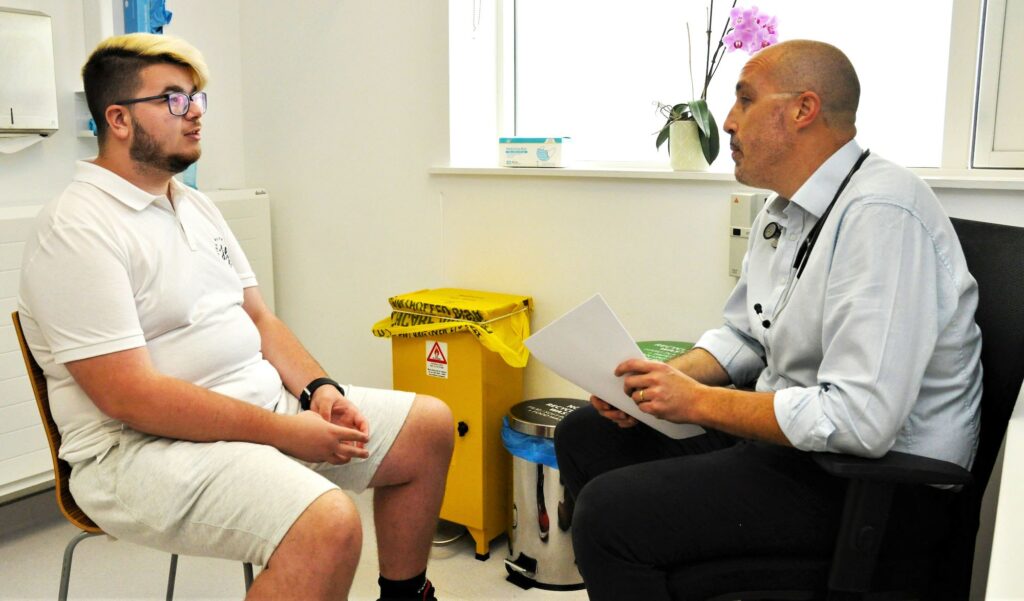 a man sitting in a chair talking to a doctor.