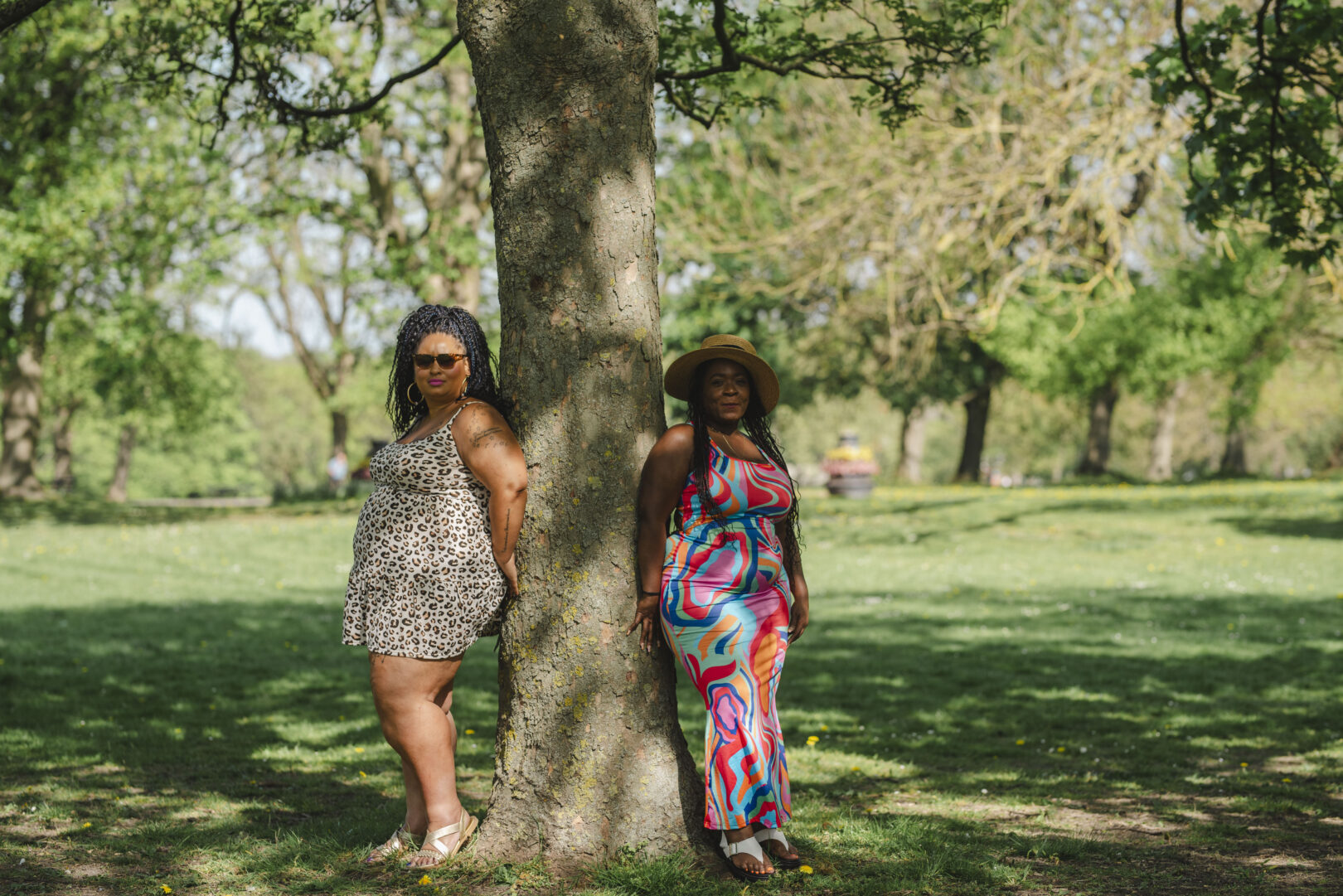 Friends standing back to back by a tree on a sunny day. Image provided courtesy of Leeds Beckett University - leedsbeckett.ac.uk