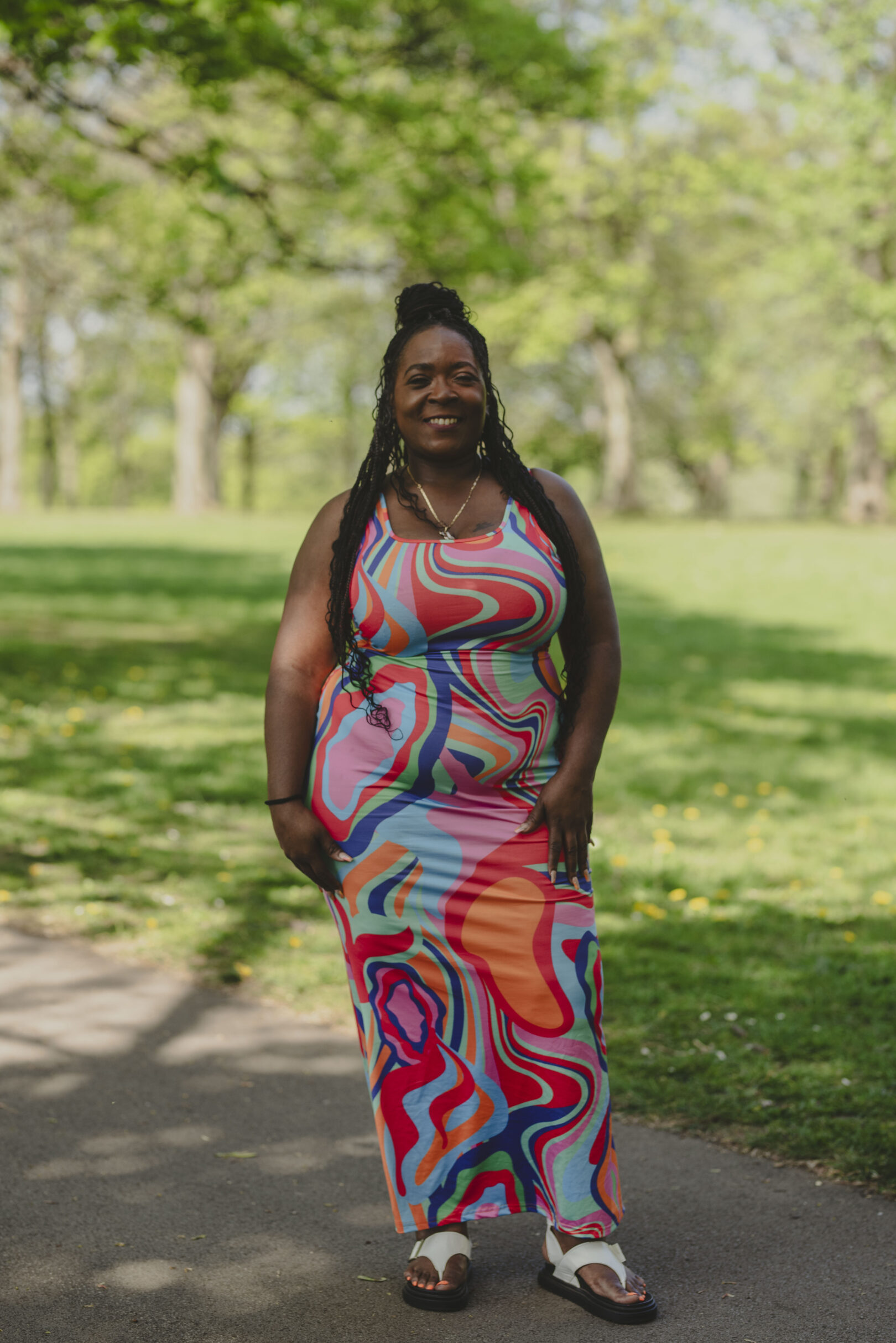 Person in a vibrant brightly coloured dress standing in a park on a sunny day. Image provided courtesy of Leeds Beckett University - leedsbeckett.ac.uk