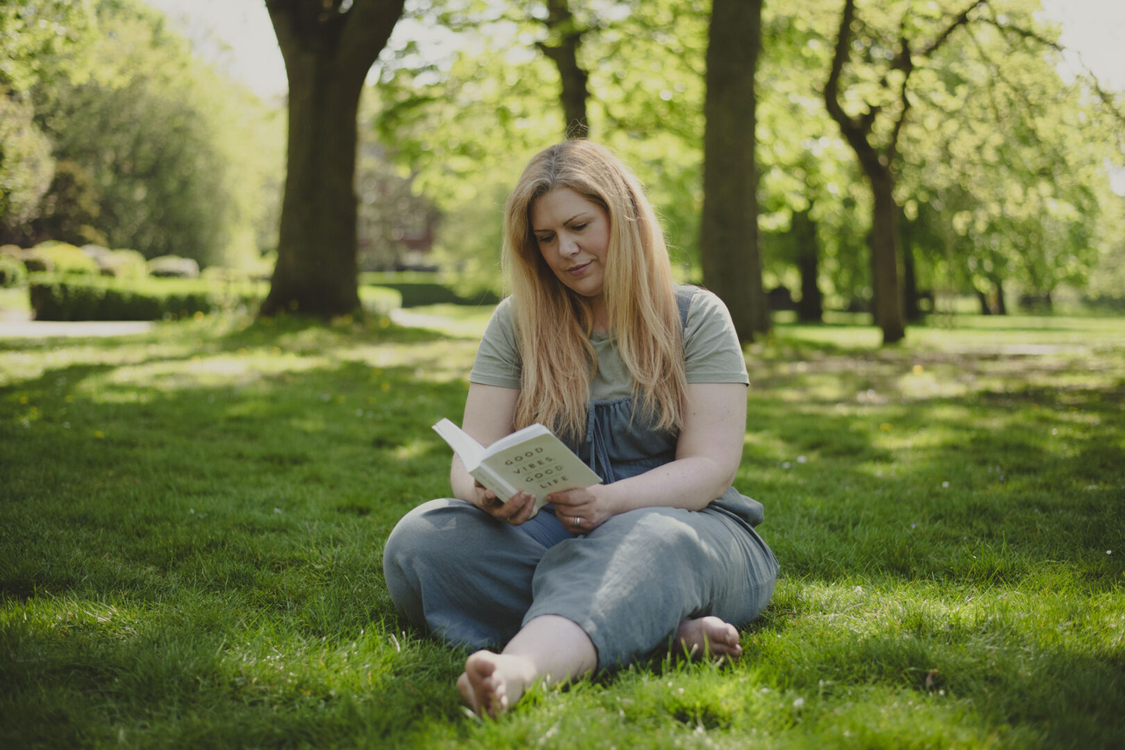 Person with long blonde hair siting on the grass in a park reading a book. Image provided courtesy of Leeds Beckett University - leedsbeckett.ac.uk